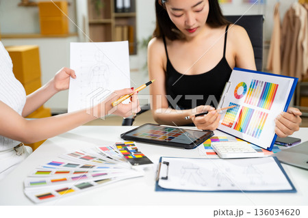Fashion designers collaborating with color palettes, sketches, and digital tools in a studio. Creative design process, branding, textile planning Fashion designers collaborating with color palettes, sketches, and digital tools in a studio. Creative design process, branding, textile planning 136034620