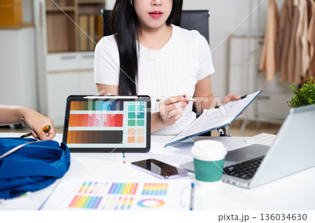 Fashion designers working together with fabric and color palette on digital tablet. Creative teamwork, textile planning and modern fashion studio concept Fashion designers working together with fabric and color palette on digital tablet. Creative teamwork, textile planning and modern fashion studio concept 136034630