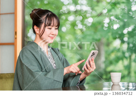 旅館の和室でスマホを見る浴衣姿の若いアジア人女性 旅館の和室でスマホを見る浴衣姿の若いアジア人女性 136034712