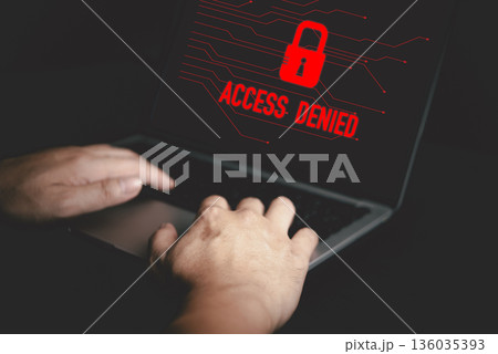 Hands typing on laptop with red Access Denied warning screen, concept of cybersecurity, hacking prevention, data breach alert, and online security protection. Hands typing on laptop with red Access Denied warning screen, concept of cybersecurity, hacking prevention, data breach alert, and online security protection. 136035393