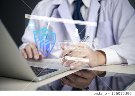 Doctor using laptop with holographic shield and lock, representing healthcare cybersecurity, patient data protection, EHR security, and digital health privacy. Doctor using laptop with holographic shield and lock, representing healthcare cybersecurity, patient data protection, EHR security, and digital health privacy. 136035396