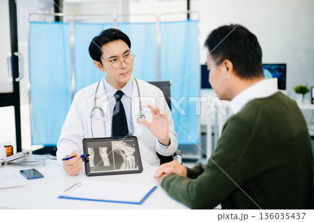 Doctor explaining knee X-ray results to patient in clinic, symbolizing orthopedic diagnosis, treatment, and modern healthcare consultation. 136035437