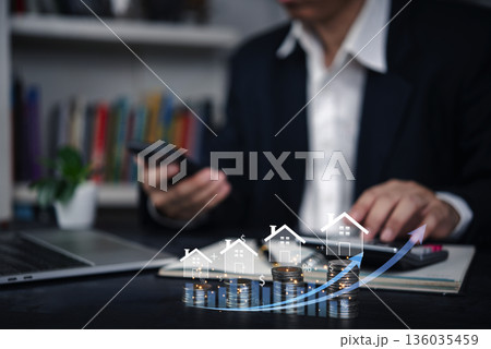 Real estate investor using a smartphone to track property growth and financial progress, with digital graphics showing increasing property values and profits. Real estate investor using a smartphone to track property growth and financial progress, with digital graphics showing increasing property values and profits. 136035459
