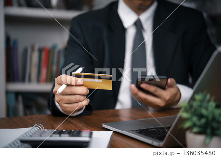 businessman using a credit card and a smartphone for secure online shopping and mobile banking. modern financial transactions, e-commerce, and digital payment security. 136035480