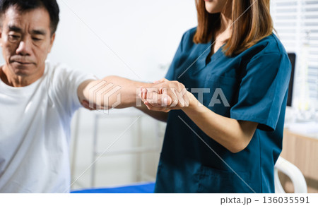 Female physiotherapist supports arm movement exercise for senior male patient during rehabilitation. Elderly care 136035591