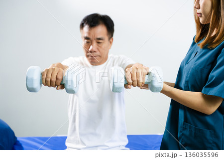 Female physiotherapist supports arm movement exercise for senior male patient during rehabilitation. Elderly care Female physiotherapist supports arm movement exercise for senior male patient during rehabilitation. Elderly care 136035596