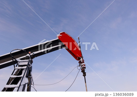 Oil Pumpjack's horsehead against blue and pink sky. Oil Pumpjack's horsehead against blue and pink sky. 136036089
