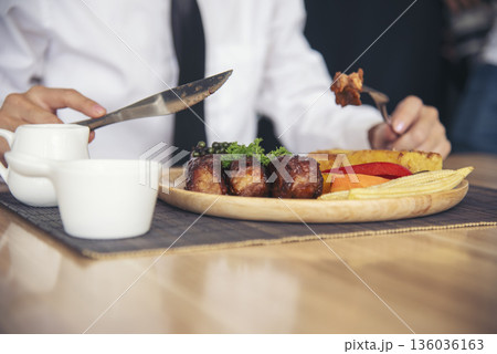 Businessman eat Steak having lunch at a restaurant. Ribs eye steak with mashed potato, salad cream French fries Barbecue Grill and Spaghetti, Happy man sitting have dinner enjoying food 136036163