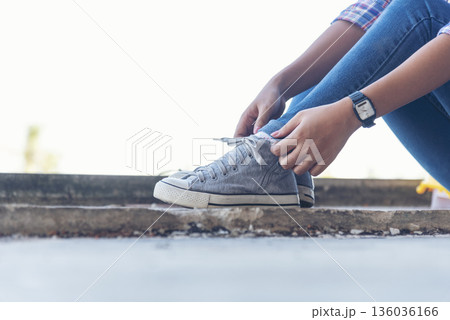 sneaker shoes young woman traveler sit down on summer park. Focus on sneaker shoes and jeans on pathway in forest park. active activity vacation on hike mountain walking way. Young traveler concept 136036166