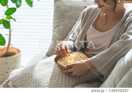 リビングのソファに座りポップコーンを食べる笑顔のアジア人女性 136038297