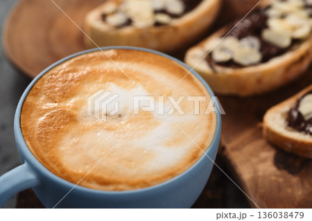 Fresh cappuccino in blue cup with toasts with chocolate spread on concrete background 136038479
