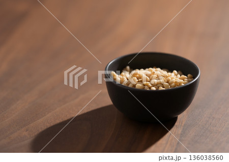 Pine nuts in a black bowl on wood table closeup Pine nuts in a black bowl on wood table closeup 136038560