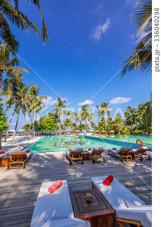 Vertical tropical beach resort infinity pool panoramic view palm trees relaxing loungers turquoise sea horizon summer luxury vacation 136040298