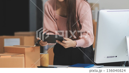 Starting small businesses SME owners female entrepreneurs check online orders to prepare to pack the boxes, sell to customers, sme business ideas online. 136040824