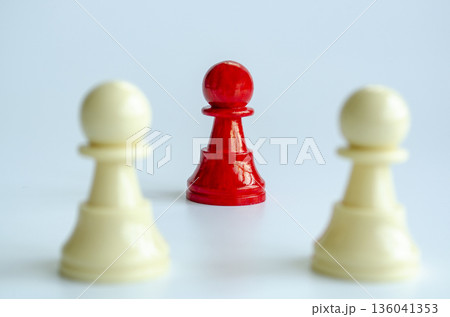 Focus on standing red pawn with two white pawns representing contrast and focus. 136041353