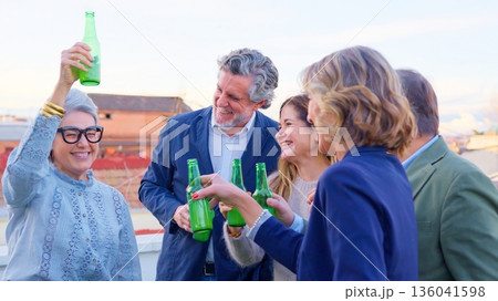 Senior friends enjoying rooftop party celebrating together drinking beer Senior friends enjoying rooftop party celebrating together drinking beer 136041598