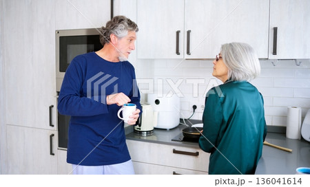 Senior couple talking and cooking in modern kitchen Senior couple talking and cooking in modern kitchen 136041614