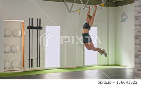 Young woman training kipping exercise in gym Young woman training kipping exercise in gym 136041622