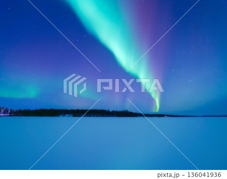 Panoramic horizontal view of the aurora borealis dancing over a frozen lake in Scandinavia.  136041936