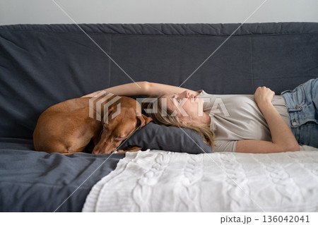 Unhappy depressed woman lying with dog at home on sofa feels apathy has mental problems. Loneliness 136042041