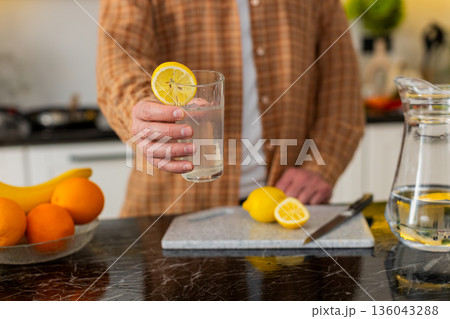 Unrecognizable man making lemon water in kitchen for healthy hydration morning wellness routine 136043288