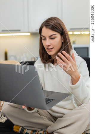 Young woman attends video interview via laptop looks at webcam answers confidently smiles and nods 136043380