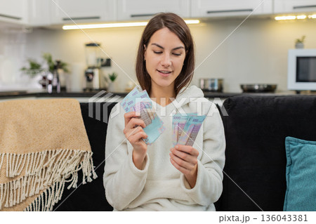 Young woman counts hryvnia money cash plans invest bonus and salary dreams of purchase future goal Young woman counts hryvnia money cash plans invest bonus and salary dreams of purchase future goal 136043381