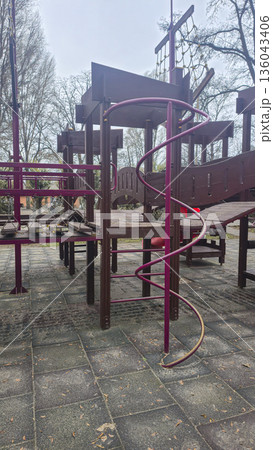 Empty swings on a playground in winter. Park attractions, wooden benches, slides Empty swings on a playground in winter. Park attractions, wooden benches, slides 136043406