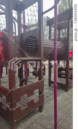 Empty swings on a playground in winter. Park attractions, wooden benches, slides Empty swings on a playground in winter. Park attractions, wooden benches, slides 136043409