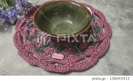 Knitted round lilac placemats on a gray background. Interior decor. Green plates. 136043415