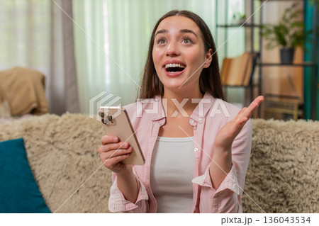 Young woman celebrates contest win after reading positive smartphone message expressing joyful shock 136043534