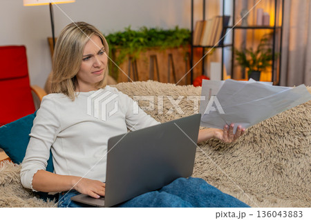 Adult woman frustrated with laptop work at home, throwing papers waving hand in irritation stress Adult woman frustrated with laptop work at home, throwing papers waving hand in irritation stress 136043883