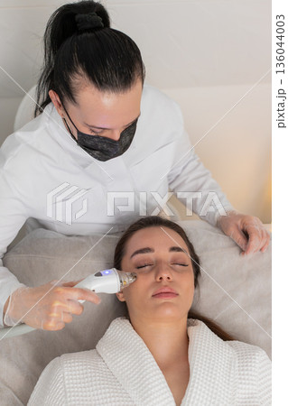 RF skin tightening around eyes for young woman by cosmetologist use beauty device in clinic session 136044003