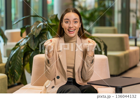 Excited successful businesswoman in formals celebrating success victory good news in office lobby Excited successful businesswoman in formals celebrating success victory good news in office lobby 136044132