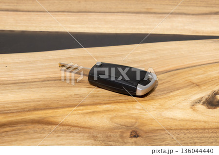 A key fob is lying on a wooden table with a smooth surface. The focus is on the key fob and the wood grain behind it 136044440