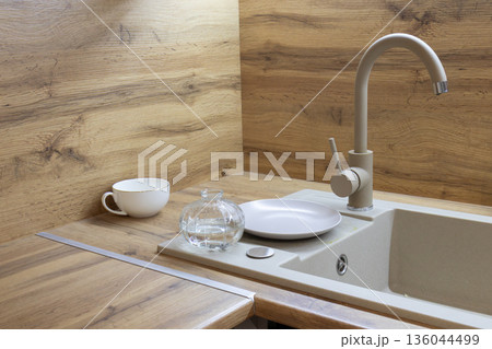 A cozy kitchen corner features warm wooden surfaces, a sleek sink, and soft lighting, creating a welcoming atmosphere for culinary creations A cozy kitchen corner features warm wooden surfaces, a sleek sink, and soft lighting, creating a welcoming atmosphere for culinary creations 136044499