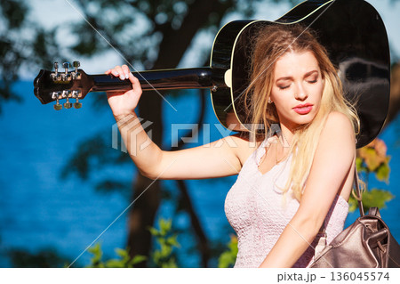 Blonde woman with acoustic guitar on seaside 136045574