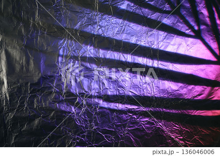 Crumpled aluminum foil surface displaying cast shadow with purple and pink light Crumpled aluminum foil surface displaying cast shadow with purple and pink light 136046006