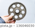 The mechanic's hand holds a gear 136046030