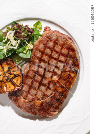 Grilled beef steak with roasted garlic and greens 136046597