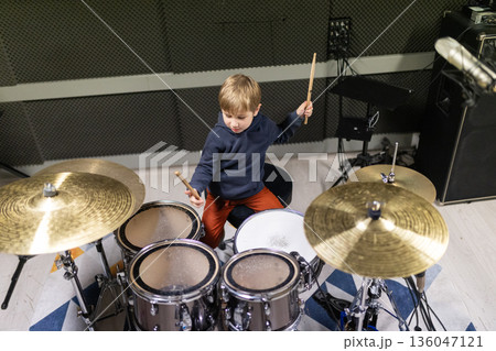 Young boy practicing drums, developing musical talent Young boy practicing drums, developing musical talent 136047121