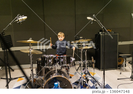 Young boy learning playing drums in music studio 136047148