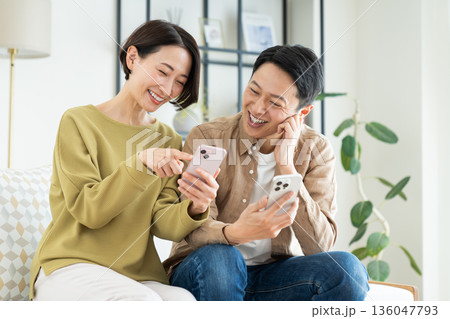 リビングでスマホを使うミドルの夫婦 136047793