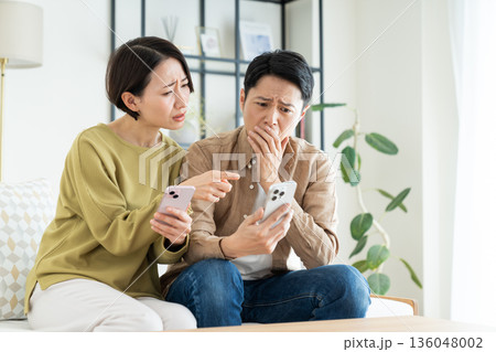 リビングでスマホを使うミドルの夫婦 136048002