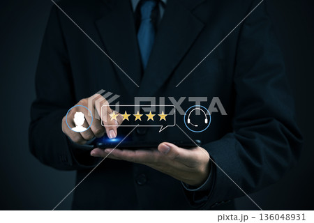 Feedback, CSAT Person in suit selects five stars on mobile at work to evaluate service experience, emphasizing positive testimonial, loyalty, and customer experience concept. 136048931