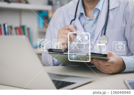 Telemedicine, doctor reviews patient data on a clipboard in clinic, using a laptop and EHR icons to streamline care and compliance. concept digital health, telehealth workflow, medical technology. Telemedicine, doctor reviews patient data on a clipboard in clinic, using a laptop and EHR icons to streamline care and compliance. concept digital health, telehealth workflow, medical technology. 136048940