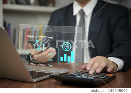 Property investment ROI , Investor uses calculator and laptop in office to analyze rental finance and realty data for growth, boosting analytics and value . concept financial strategy. 136049065