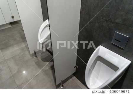 Two modern urinals stand side by side in a clean, minimalist restroom, showcasing sleek lines and polished surfaces Two modern urinals stand side by side in a clean, minimalist restroom, showcasing sleek lines and polished surfaces 136049671