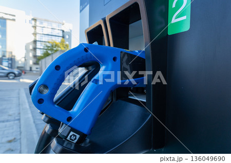 Bright sunshine illuminates a sleek gas station, showcasing the blue pump handle ready for fueling up vehicles 136049690