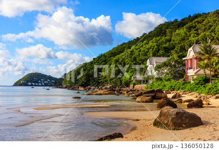 A beach with a rocky shoreline and a house in the distance 136050128